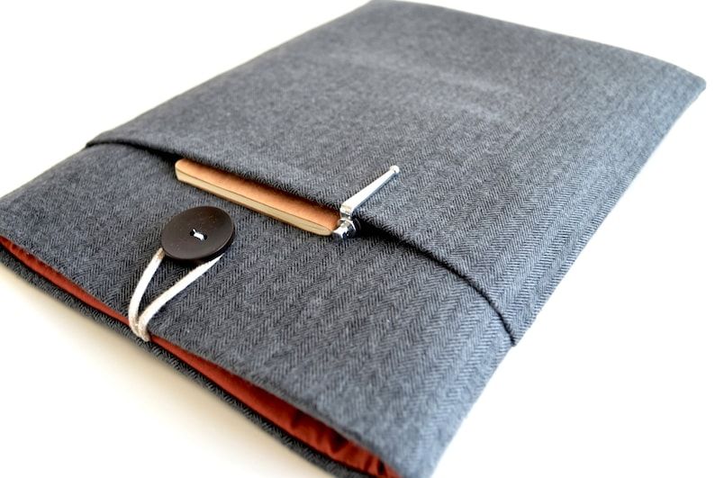 A gray herringbone reader sleeve with a button enclosure, orange lining, and an outside  pocket.