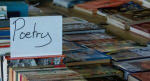Image of table of books with handwritten sign reading "poetry"