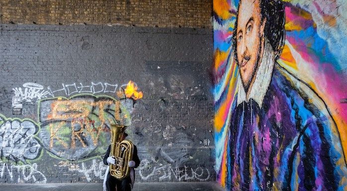 Image of tuba player in front of shakespeare painting