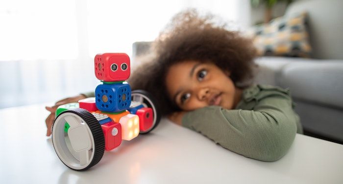 Image of a young Black girl looking at a toy robot