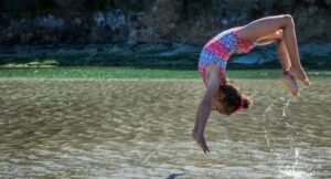 image of young girl flipping in a lake