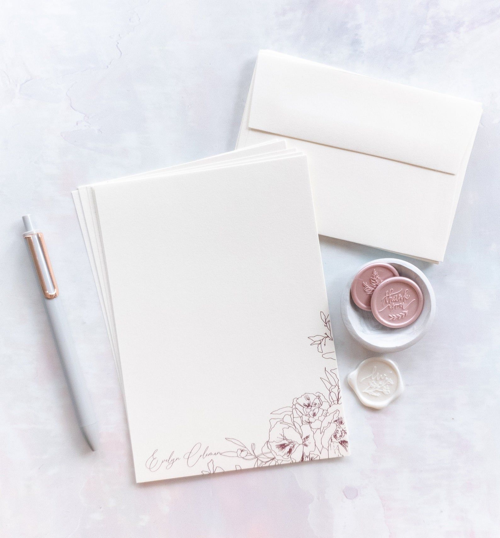 Image of stationary kit featuring creamy paper with rose-colored flowers. 