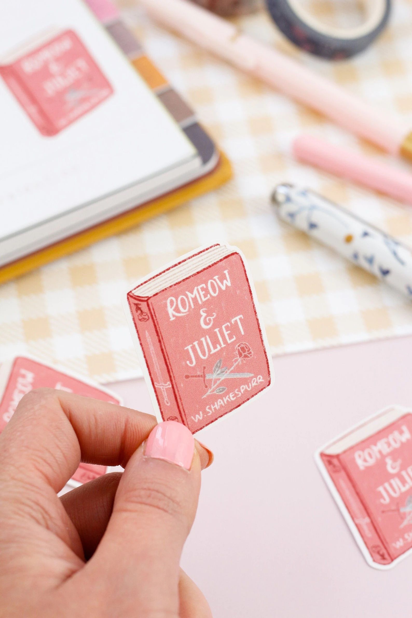 pink stickers in the shape of a book with the words Romeow & Juliet on the cover