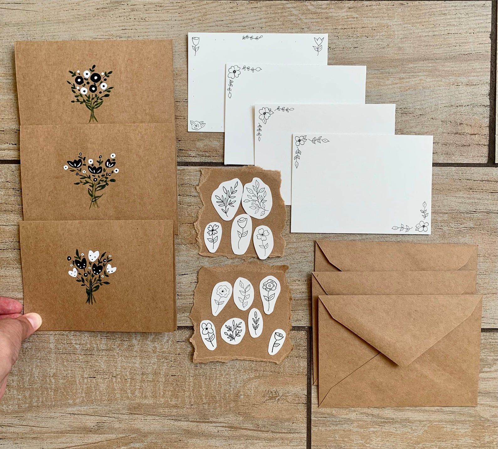 Image of minimalist flower design on brown envelopes and cream paper. 