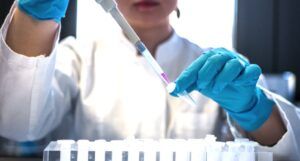 scientist pipetting colored chemicals into a tube