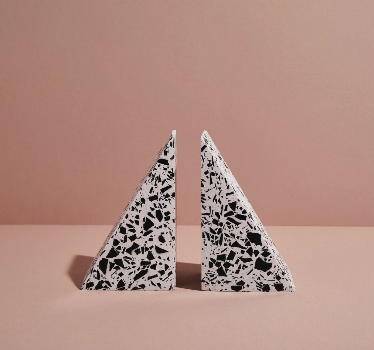 Pair of white bookends flecked with black. They are in the shape of triangles. 