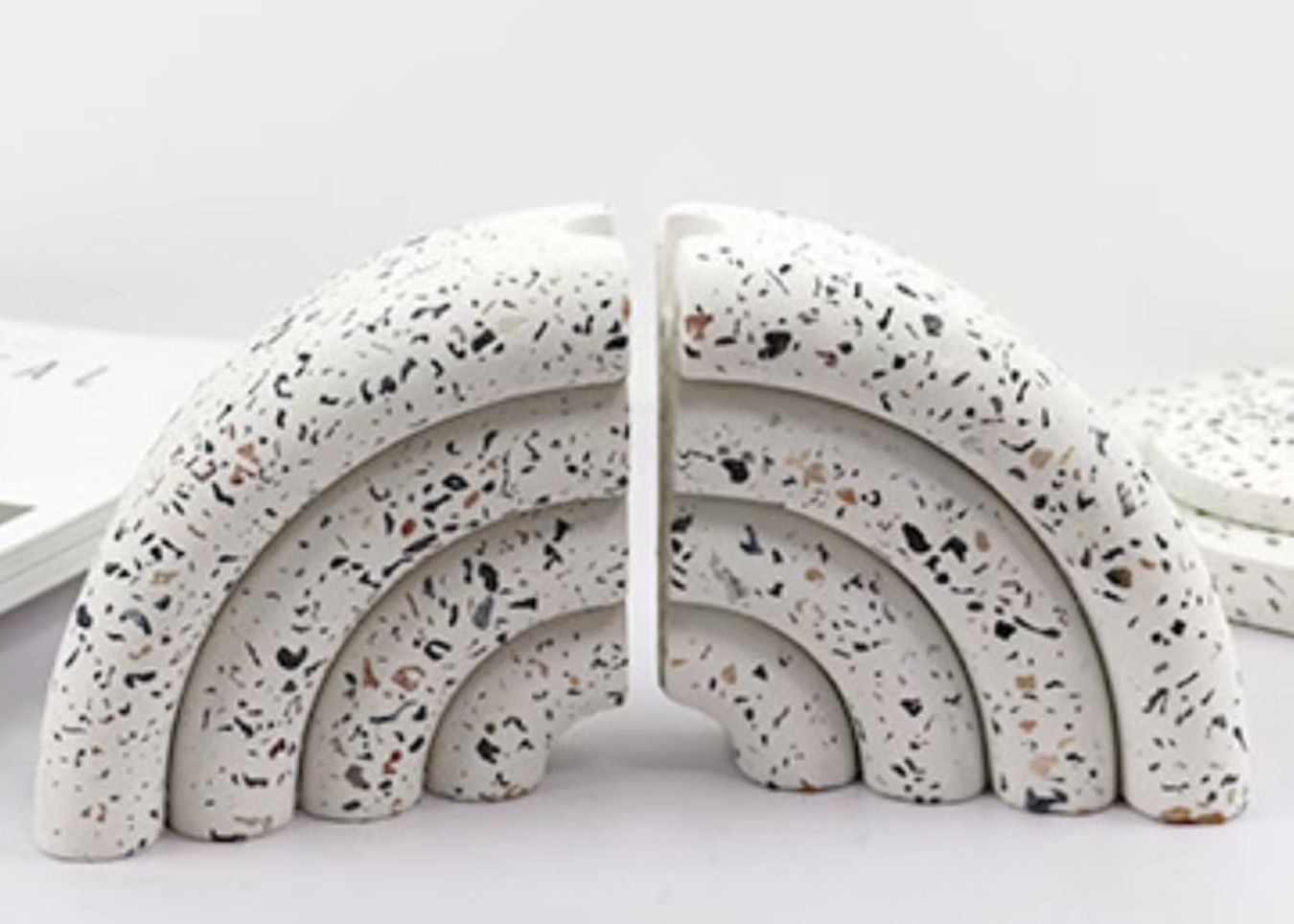 Pair of white terrazzo bookends in the shape of an arch.