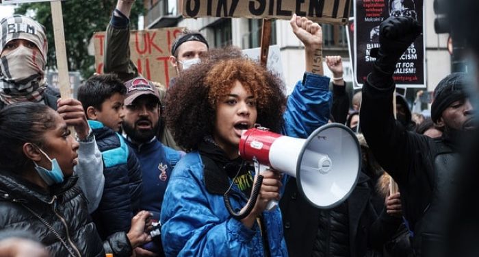 Black woman with megaphone protesting with group of people