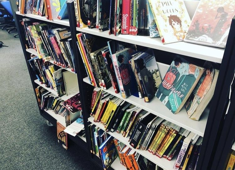 A shelf of comic books with lots of extra room. Some books are faced out.