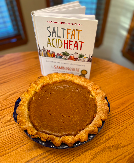 Pumpkin pie with small cracks, with Samin Nosrat's Salt Fat Acid Heat cookbook