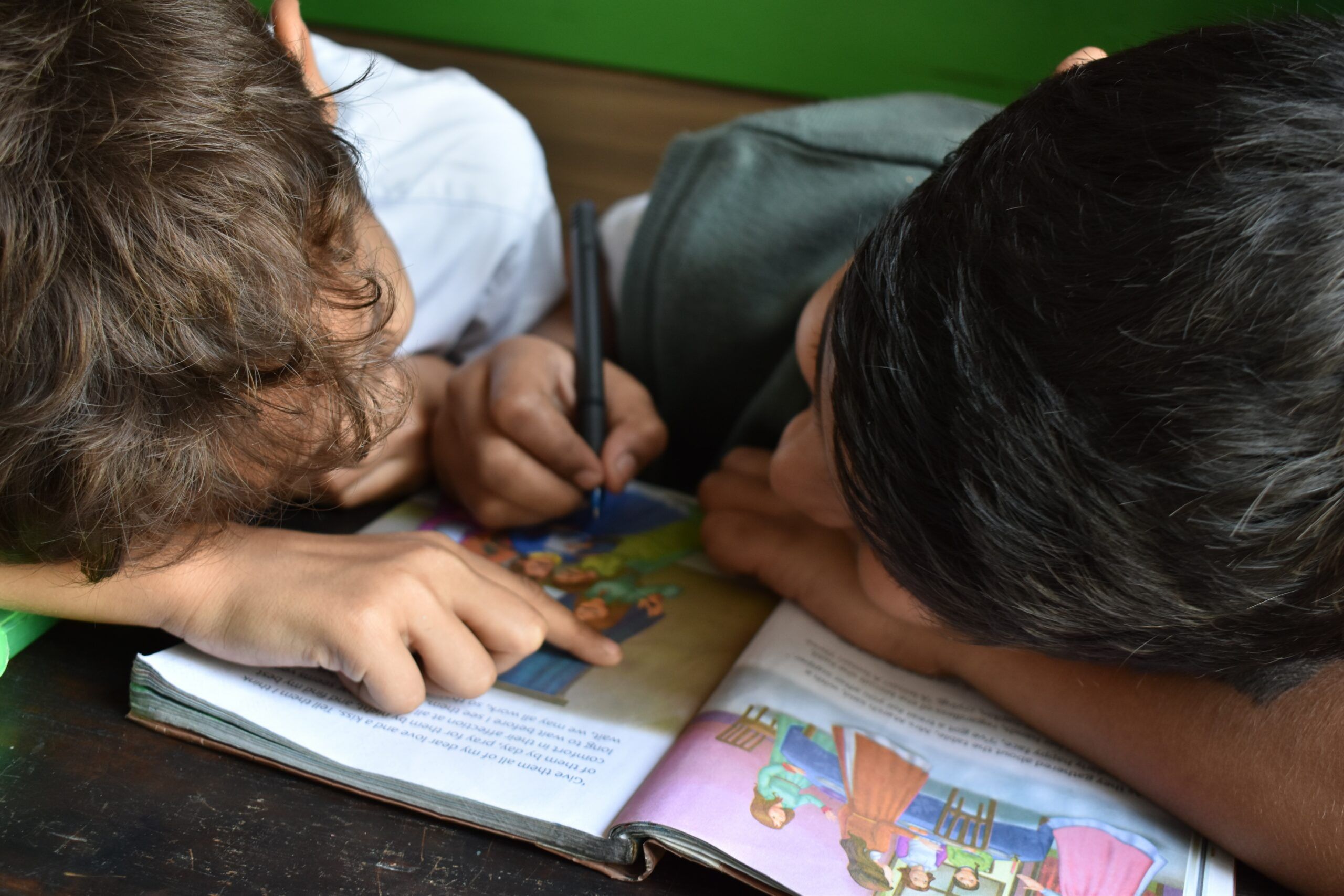 two boys writing on book