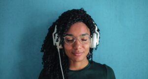 a person with their eyes closed wearing a pair of white over-ear headphones