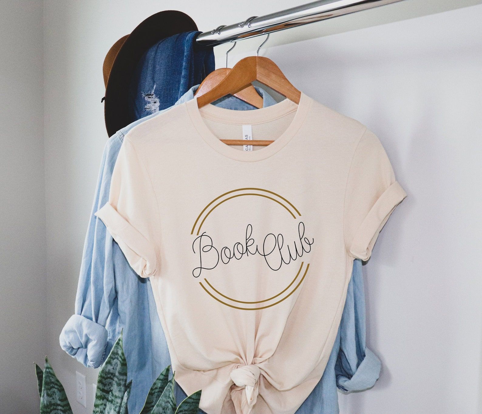 Image of a peach colored shirt. In the center are the words "book club" in a swirly font. 