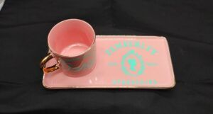 A pink tray with matching mug that reads Pemberley Est. 1813 in blue script.