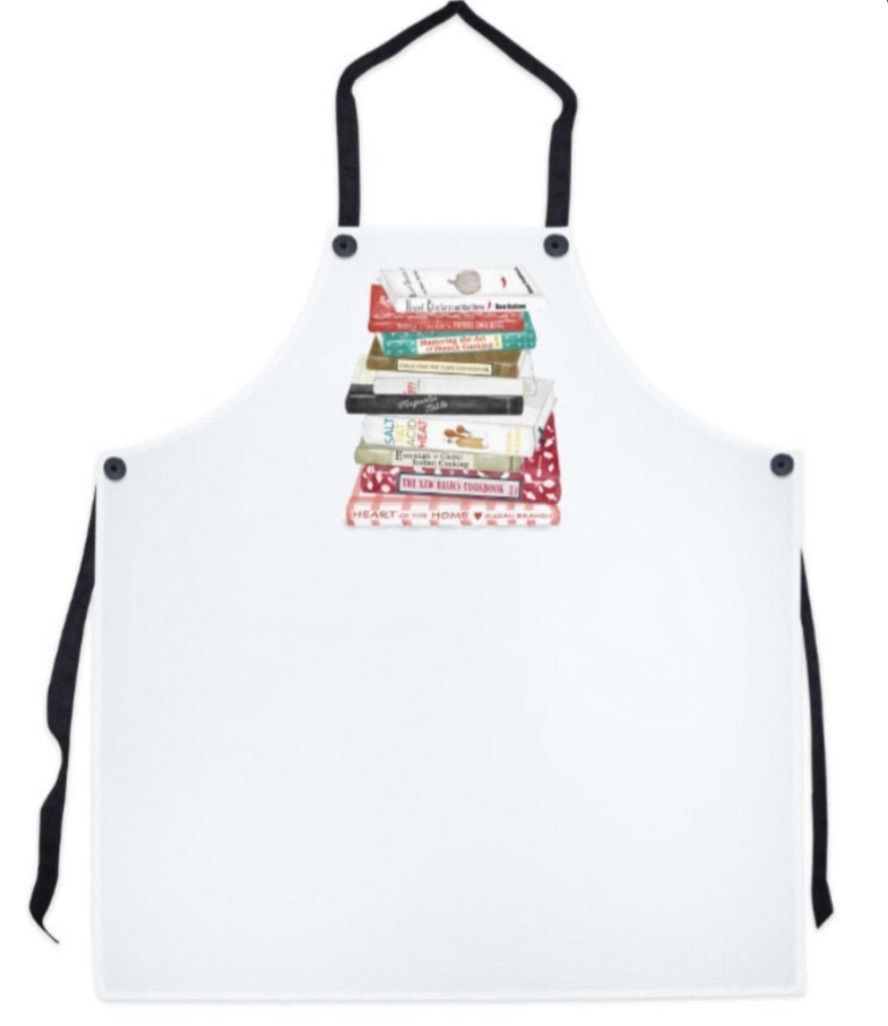 Image of a white apron. On the apron is a stack of classic cookbooks. 