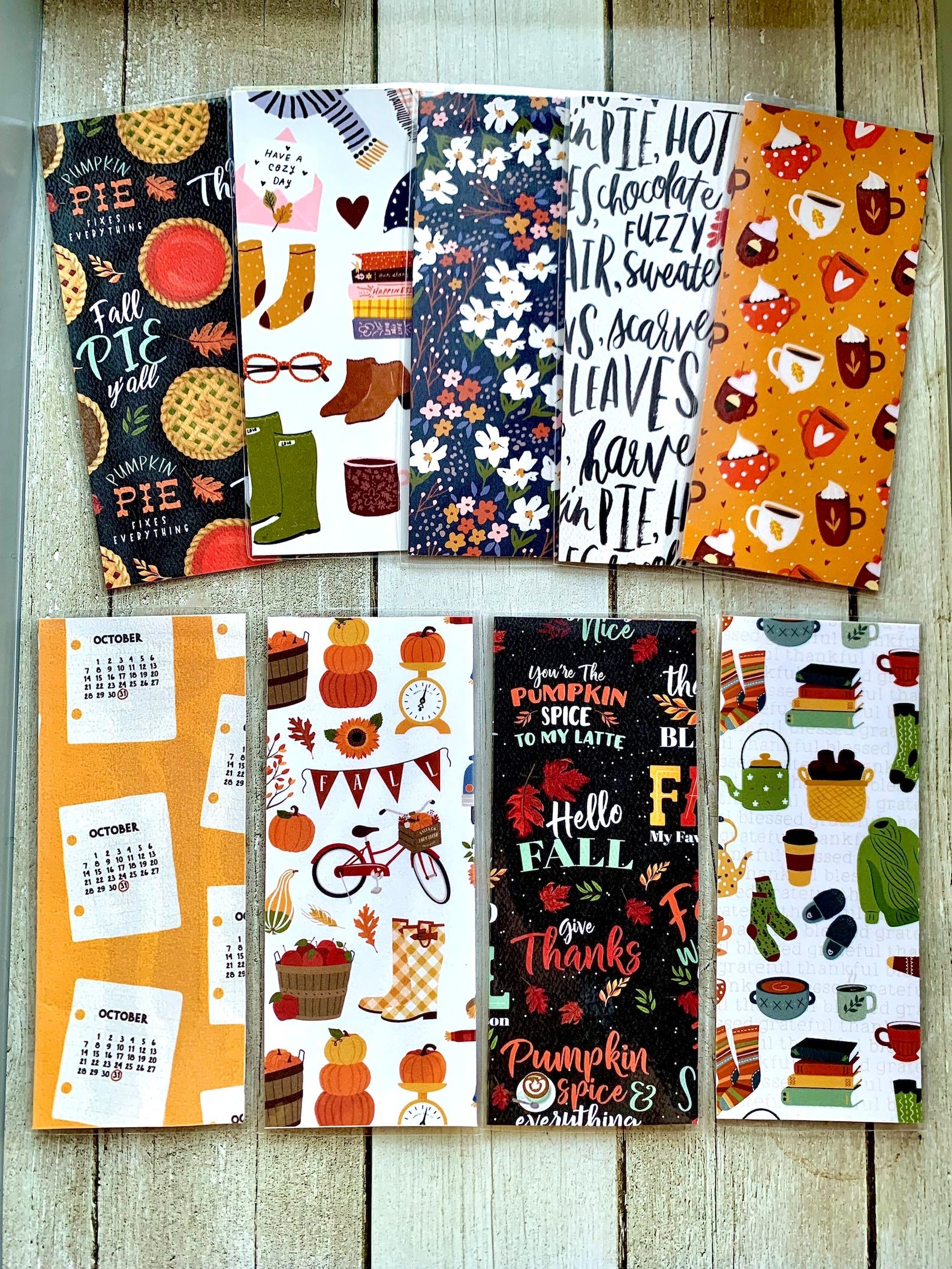 Eight bookmarks in various fall motifs of pumpkin spice lattes, green sweaters, fall florals, and pumpkin pies.