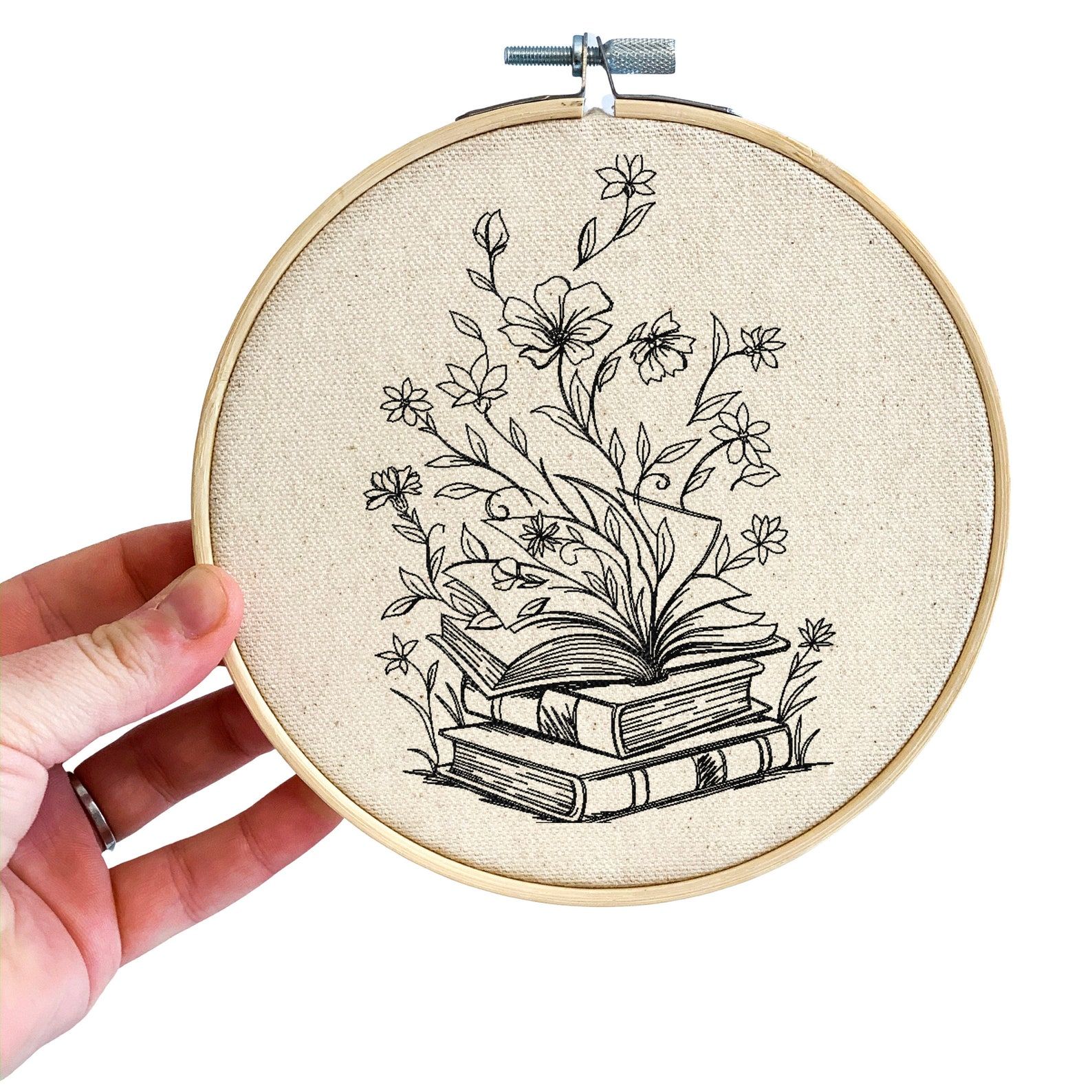 Image of an embroidery featuring open books and flowers coming out. 