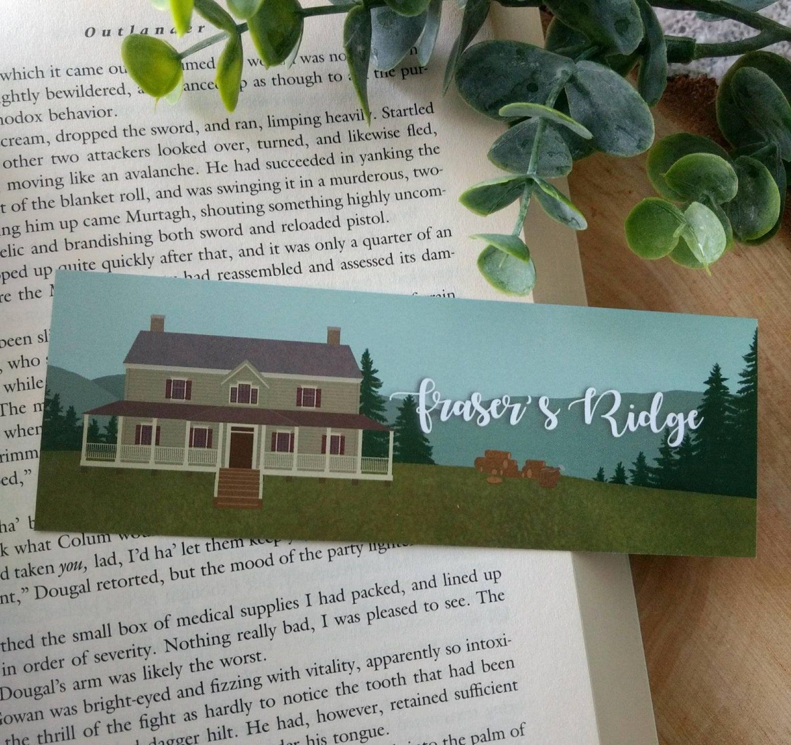 bookmark depicting blue mountains and a grand house, with the words "Fraser's Ridge"