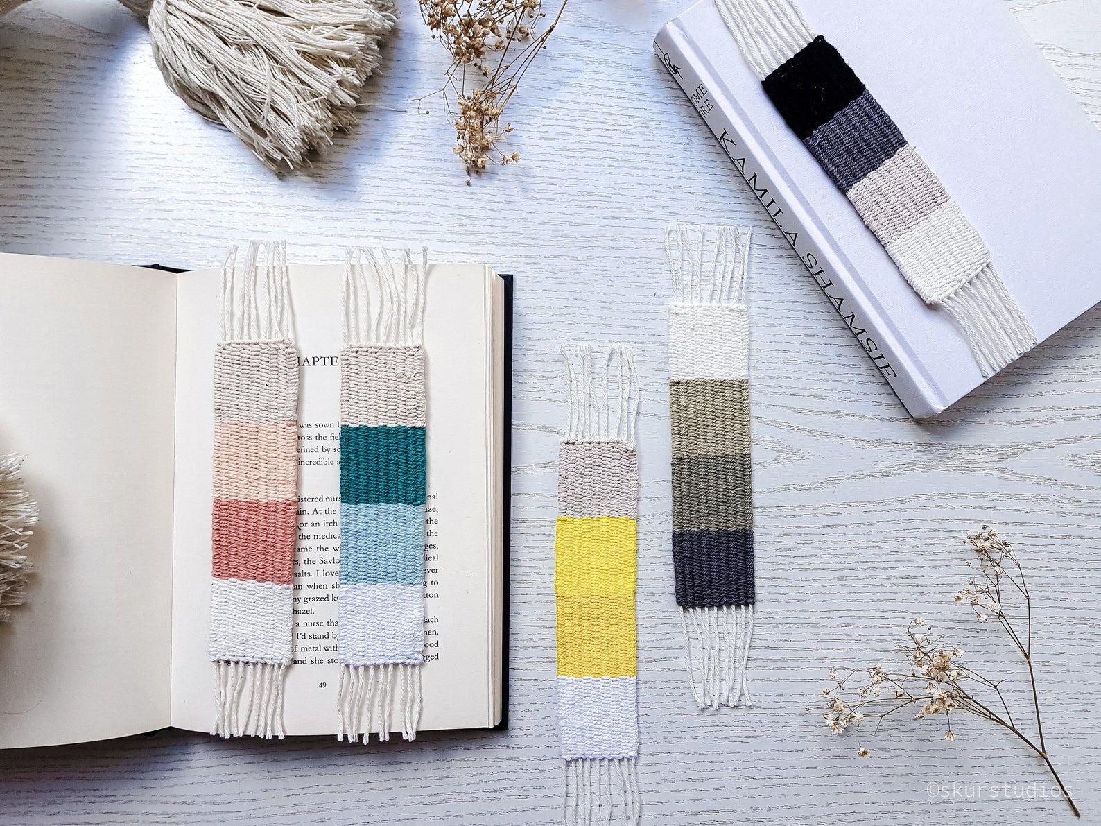 Image of five different handmade, woven bookmarks in a number of colors. 