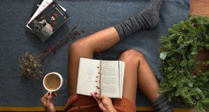Image of black skin legs with socks, a book, and cup of coffee