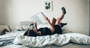 Image of a dark haired girl reading on a bed