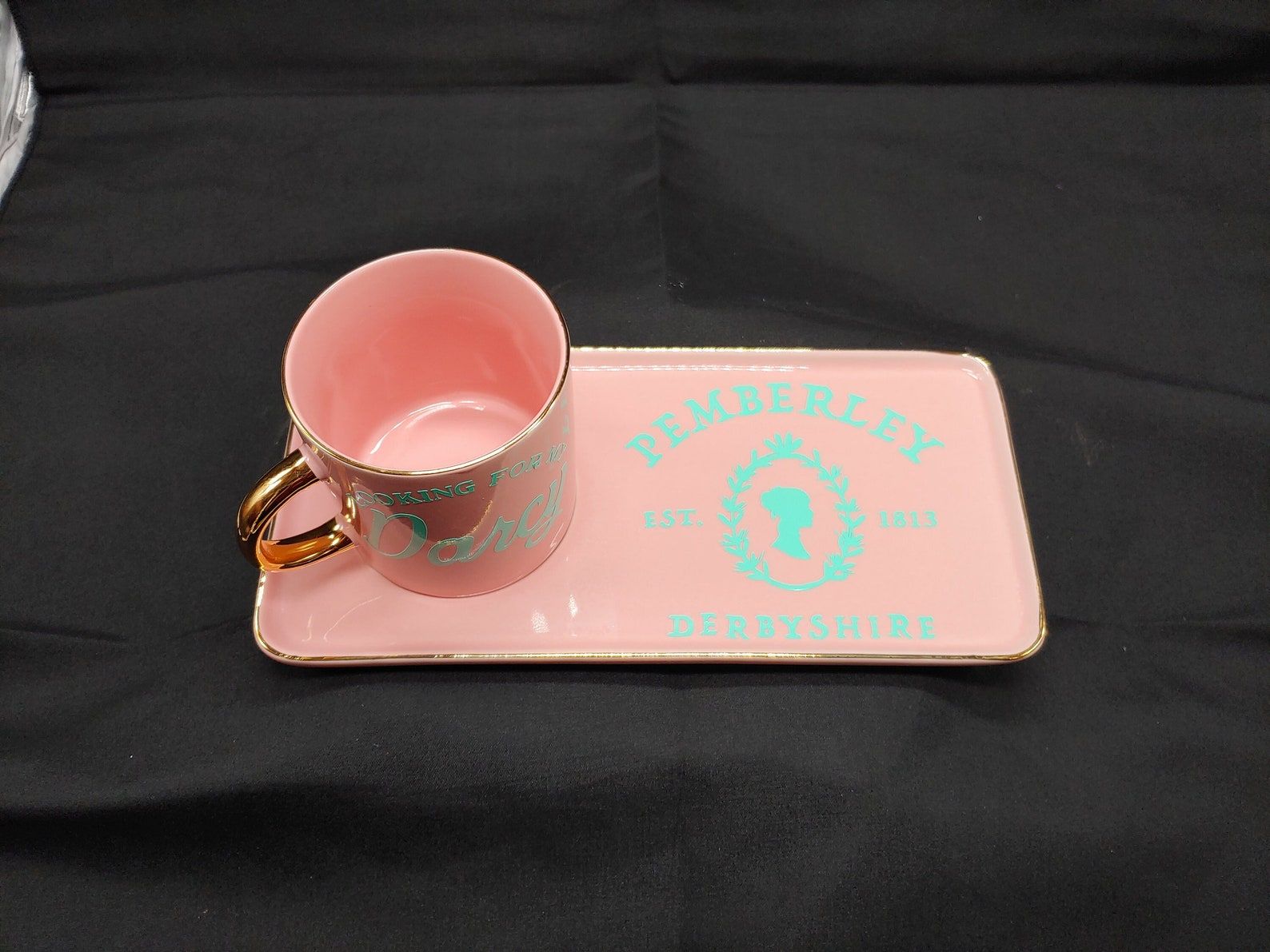 A pink tray with matching mug that reads Pemberley Est. 1813 in blue script.