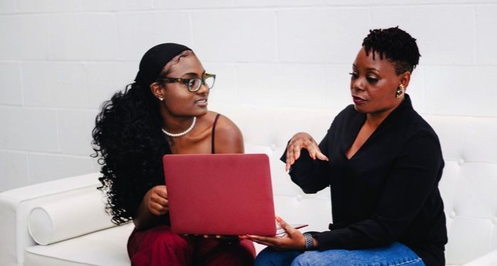 two seated people looking at a laptop computer together