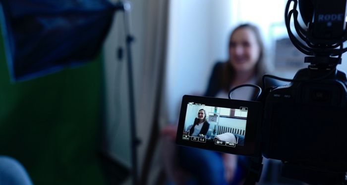 a video camera aimed at a woman seated in a chair