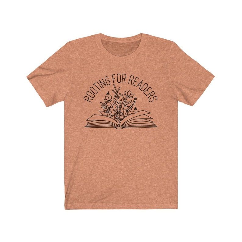 Image of an orange t-shirt with the words "rooting for readers." Below the text is a book with flowers rising from the center. 