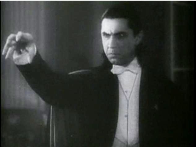 Une image en noir et blanc de Bela Lugosi dans le rôle de Dracula dans le film du même nom de 1931.  Il porte un smoking blanc et une cape sombre, étendant sa main dans une griffe effrayante. 