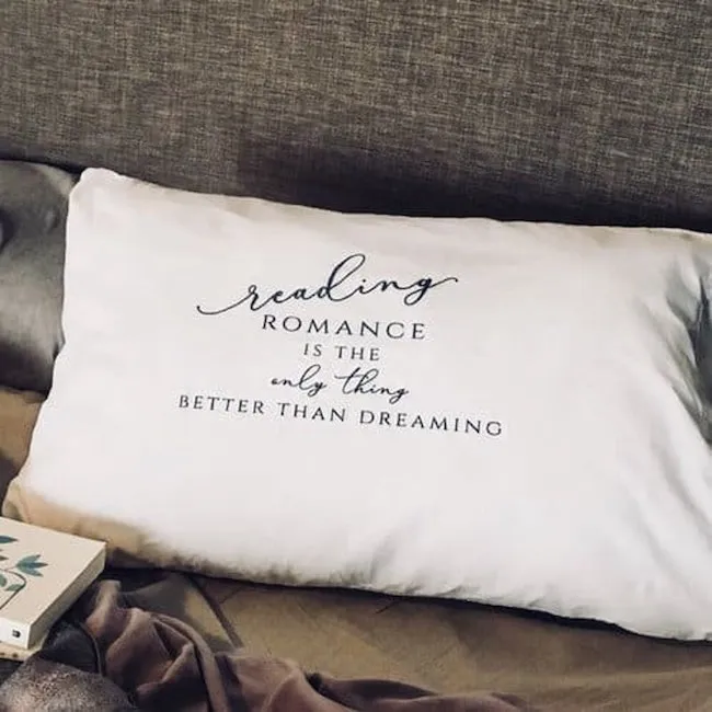 A white pillowcase with black text that reads, "reading romance is the only thing better than dreaming." 