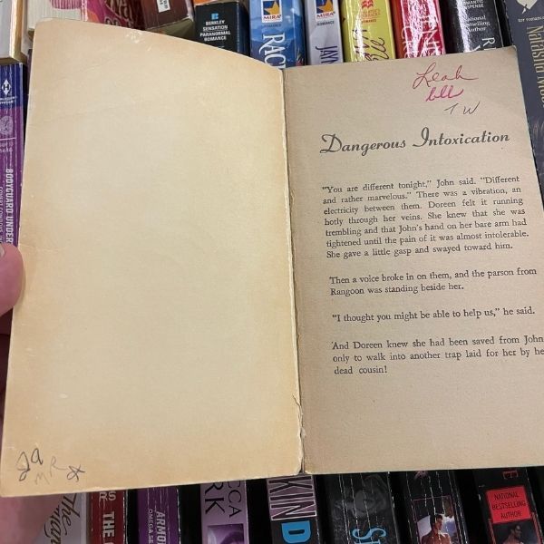 The inside front cover and front page of a romance novel, with six names and initials written in different handwriting.