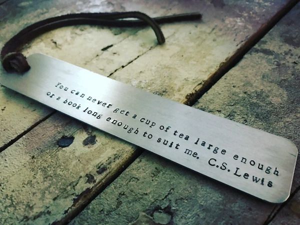 metal book mark with handstamped letters reading "you can never get a cup of tea large enough or a book long enough for me"