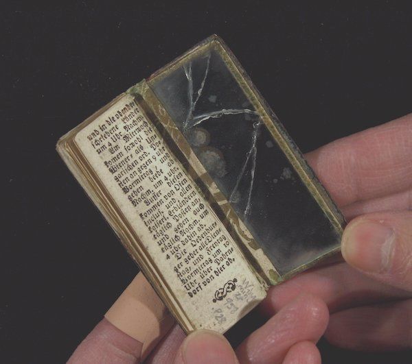 An open miniature book with the backcover as a mirror