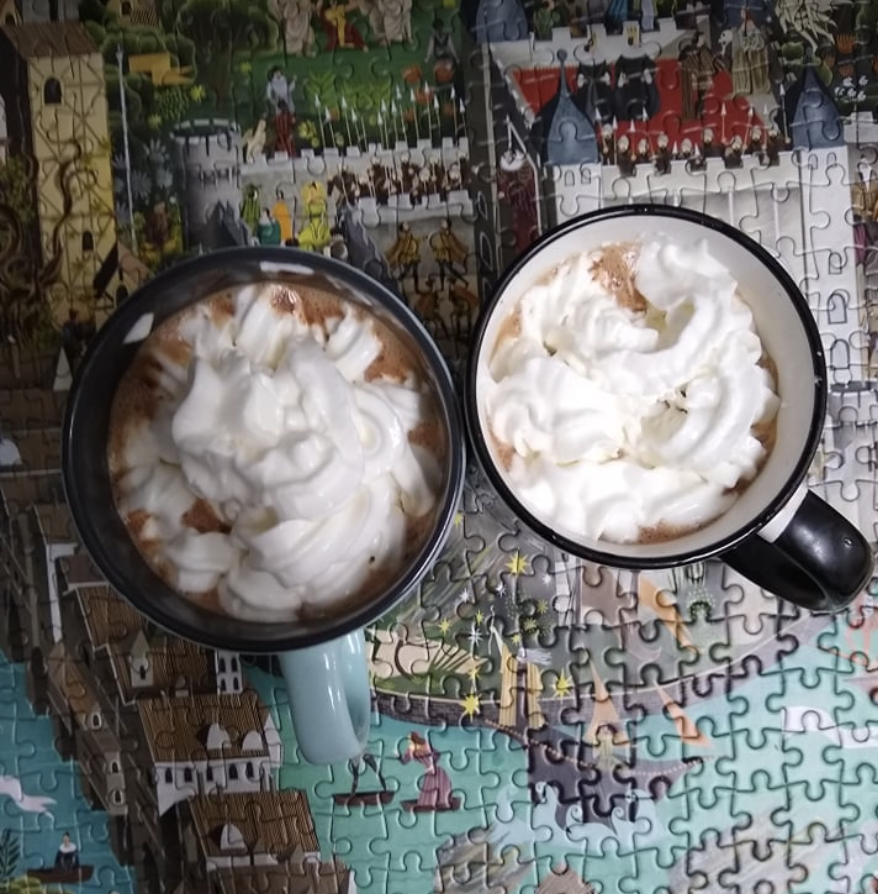 two cups of hot cocoa as prepared from Junk Food to Joy Food. The mugs are on top of a finished puzzle. 