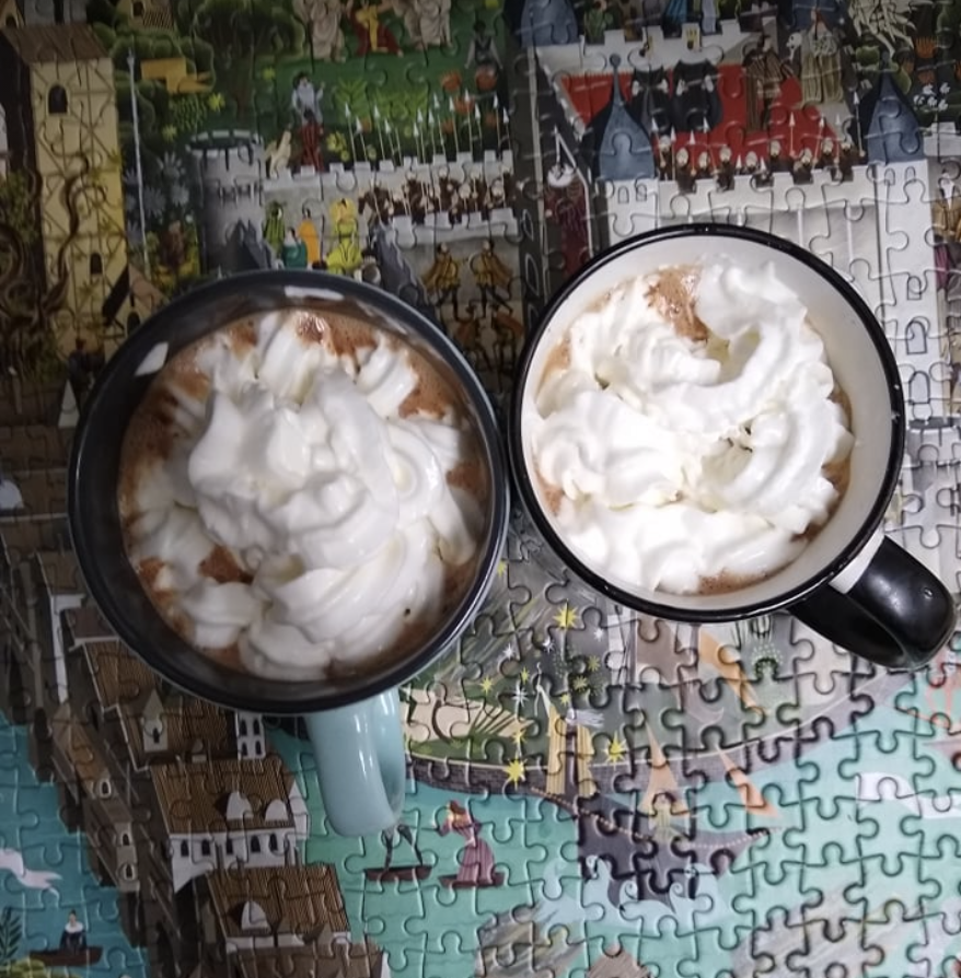 deux tasses de chocolat chaud tel que préparé de Junk Food à Joy Food.  Les tasses sont au-dessus d'un puzzle fini. 