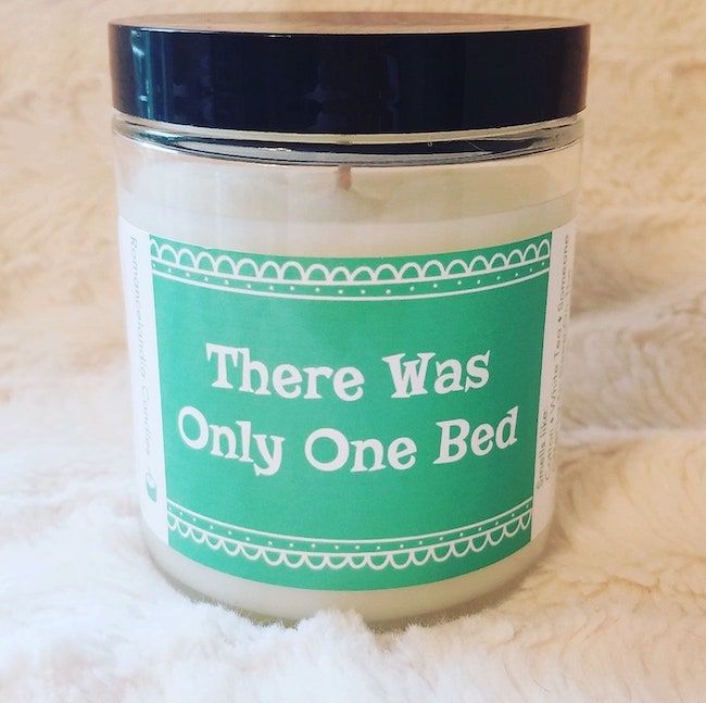 A 7-ounce white candle in a glass jar with a black top and a mint-green label that reads, "There Was Only One Bed." It is "Clean Cotton" scented. 