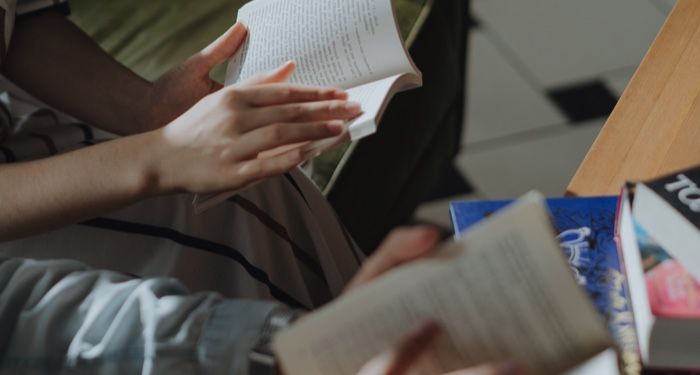 two sets of hands holding open paperback books