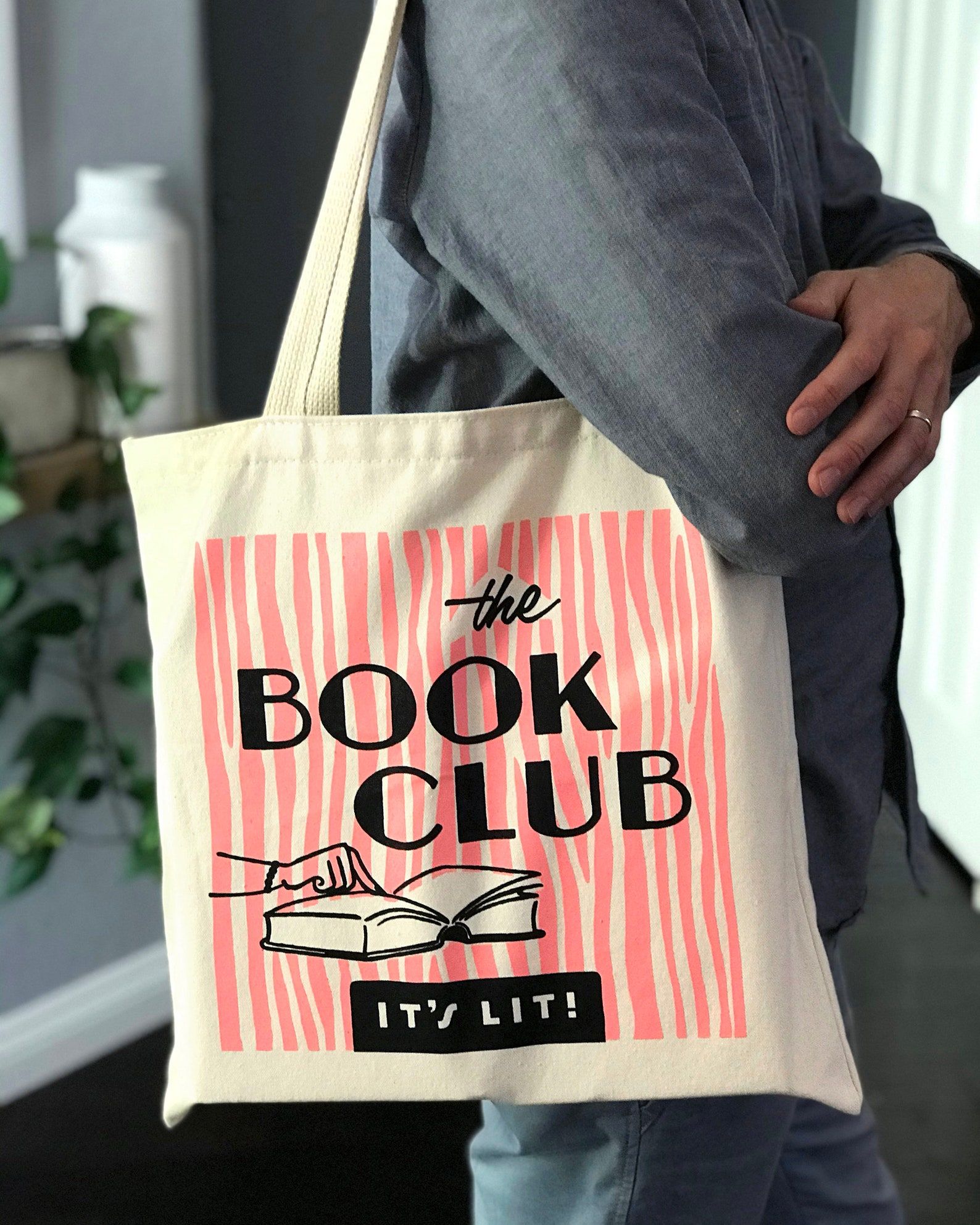 Image of a canvas tote bag. It's got pink stripes and the words 