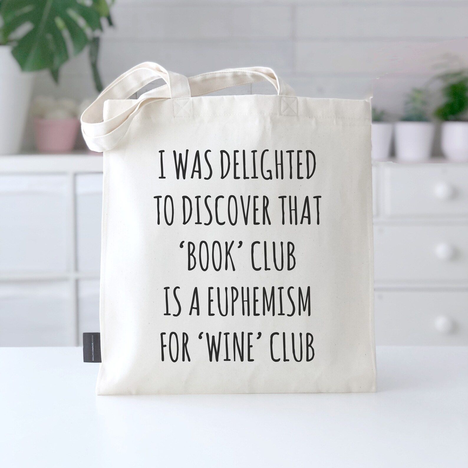 Tote bag with plain black writing saying "I was delighted to discover that book club is a euphemism for wine club"