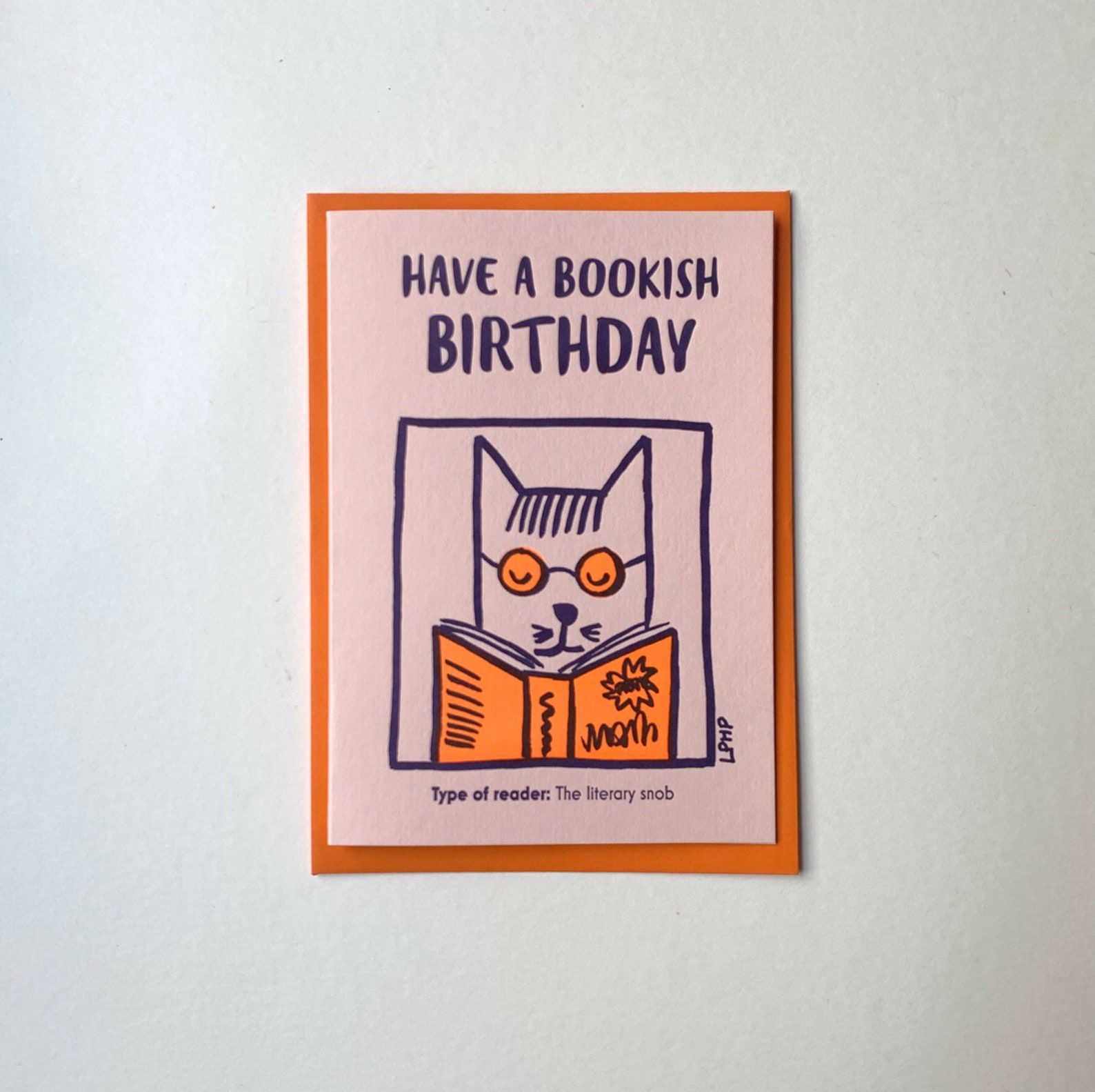 Image of a birthday card. It's pink with a cat on it. 