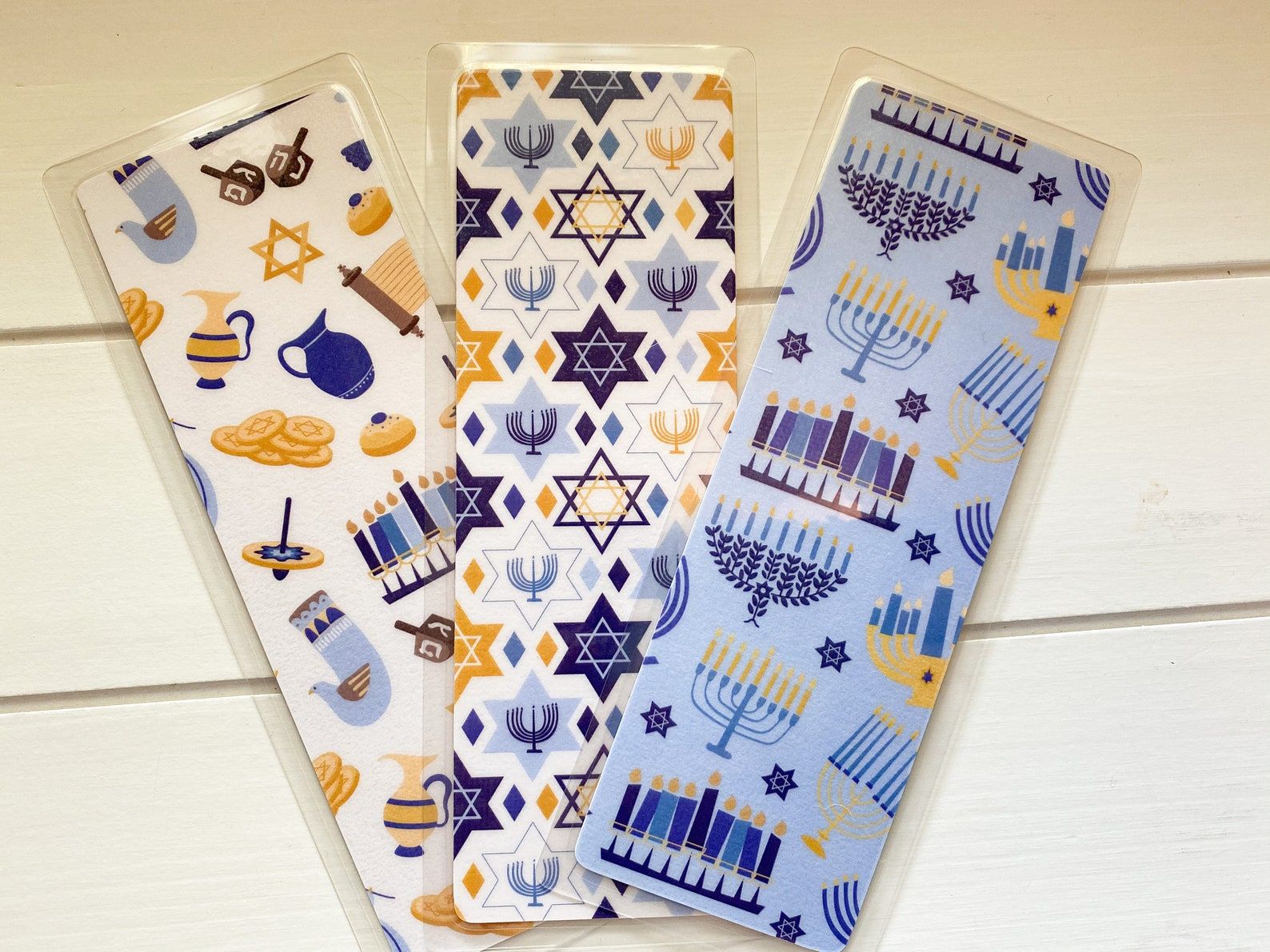 Image of three Hanukkah themed bookmarks celebrating the menorah, eight nights, and an array of symbols associated with the celebration. 