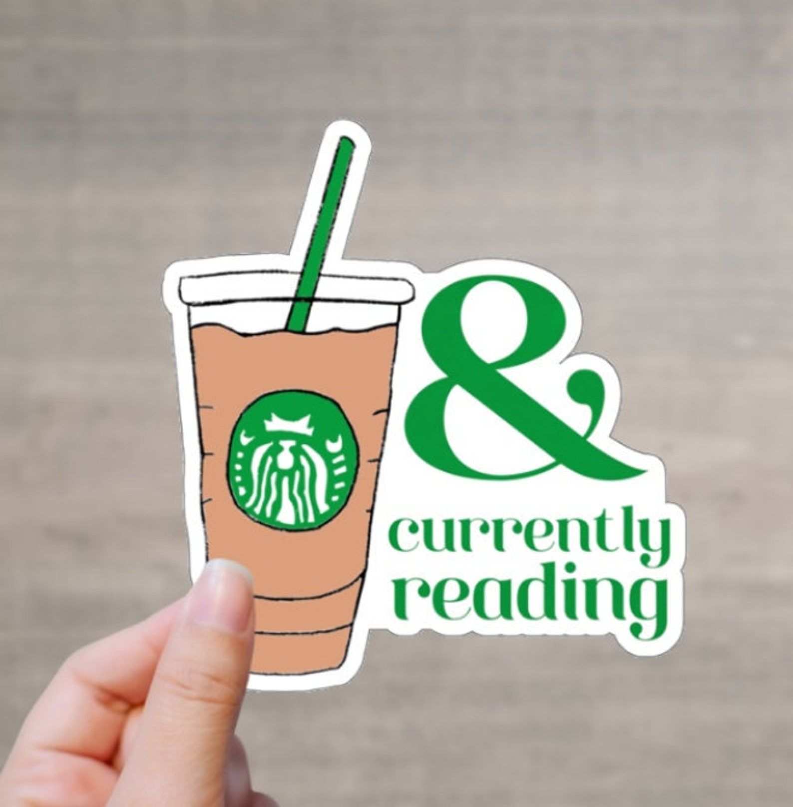 A sticker depicting a Starbuck iced coffee and "& currently reading"