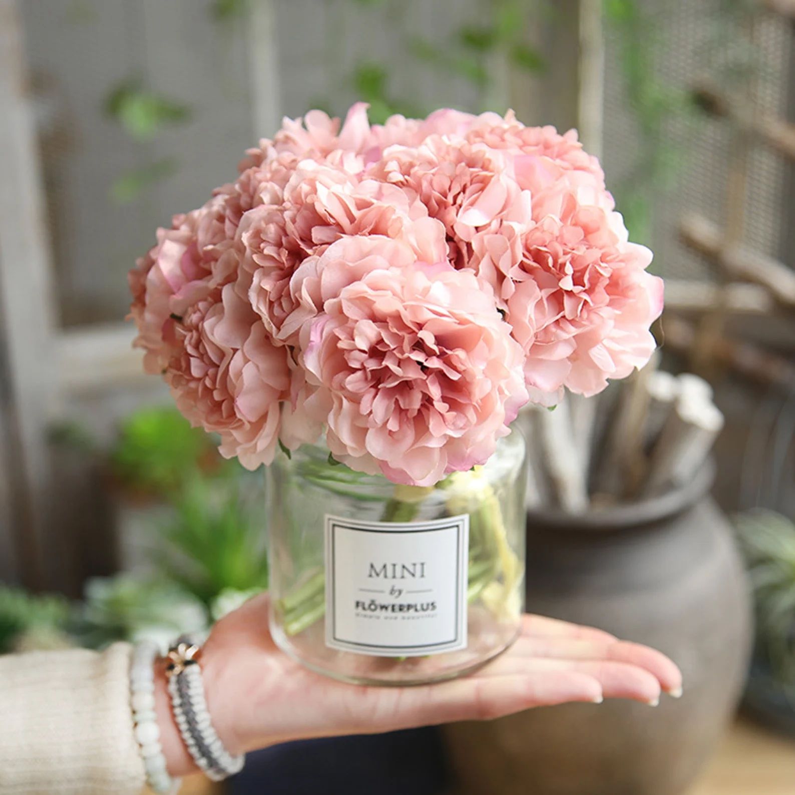 Photo de fleurs de pivoine en soie artificielle rose dans un vase en verre.