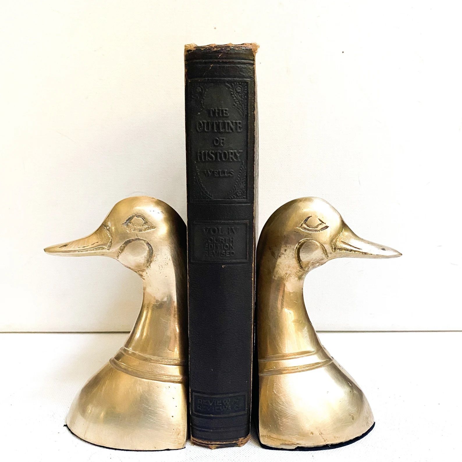 Cadeau pour amoureux des livres : deux bouts de livre de canard doré de chaque côté d'un livre vintage marron foncé.