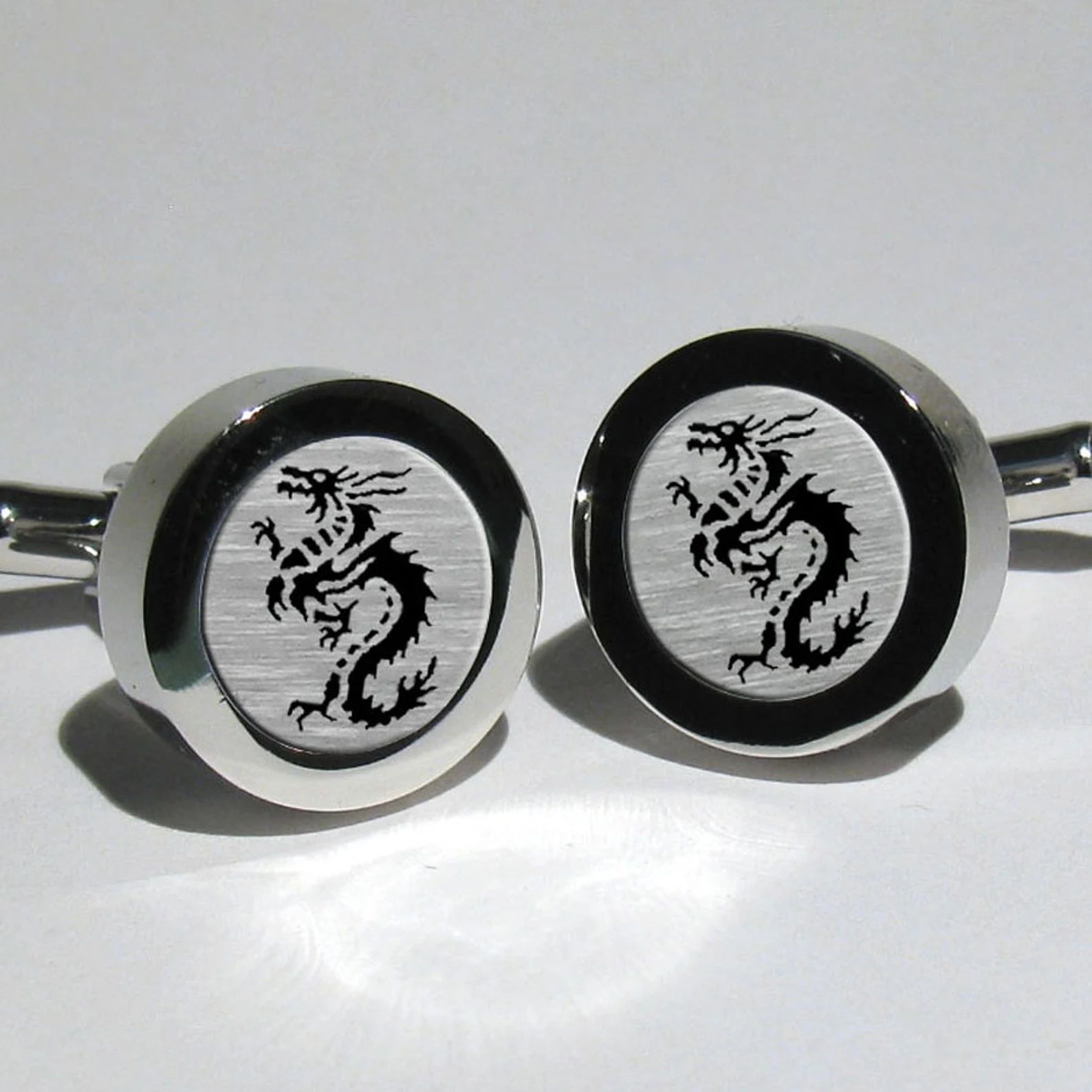 Boutons de manchette en argent et noir avec des dragons dessus.