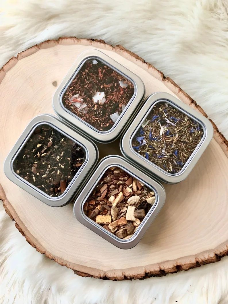 Four tins of multicolored loose leaf tea mixes.