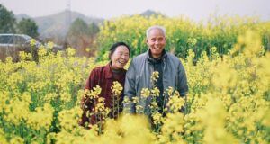 Image of an Asian couple who is older in a yellow field