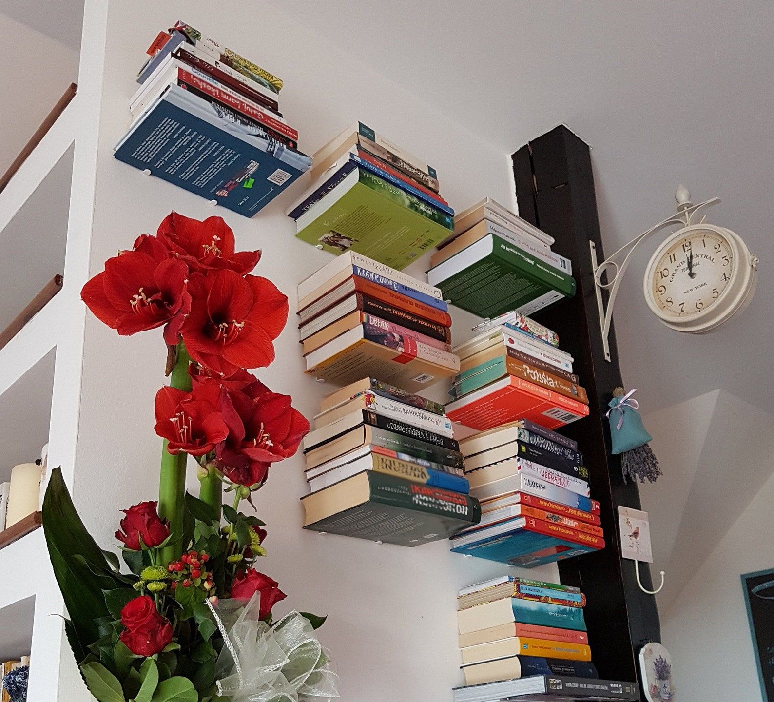 étagères métalliques flottantes invisibles empilées de livres le long d'un mur, à côté d'une plante à fleurs