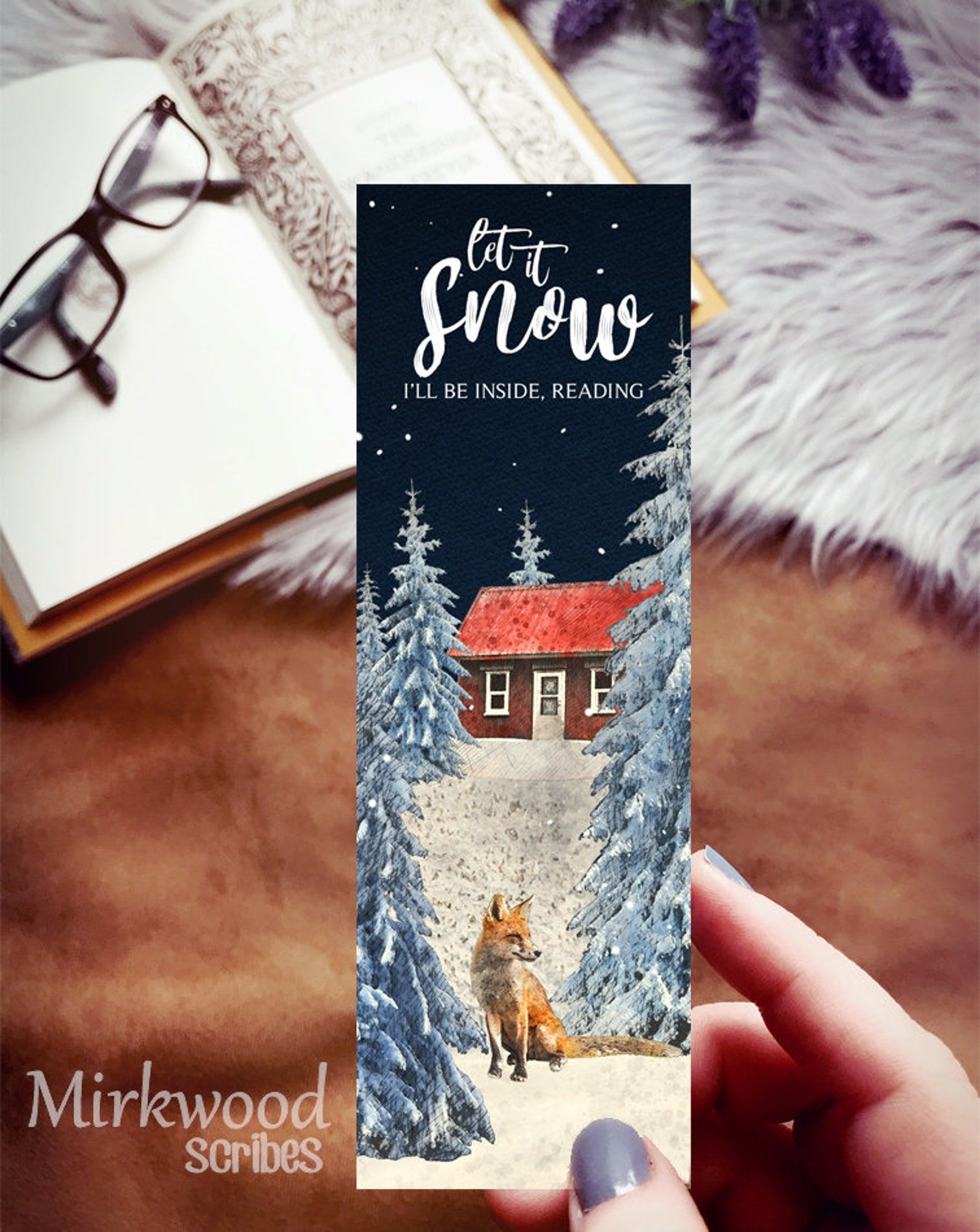 Image of a bookmark with a fox, pine trees, and a cabin. It reads "Let it snow."